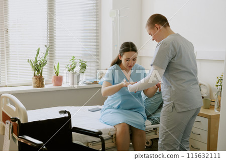 Young nurse helping pregnant patient with standing up while patient having contractions Young nurse helping pregnant patient with standing up while patient having contractions 115632111