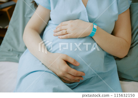 Future mother caressing her pregnant tummy in hospital ward 115632150
