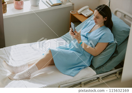 High angle shot of pregnant woman lying on hospital bed and texting in social network High angle shot of pregnant woman lying on hospital bed and texting in social network 115632169