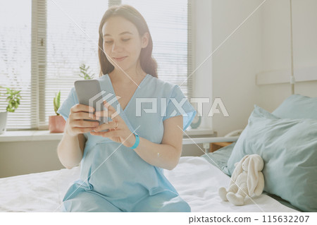 Young pregnant woman chatting via phone while staying at maternity hospital 115632207