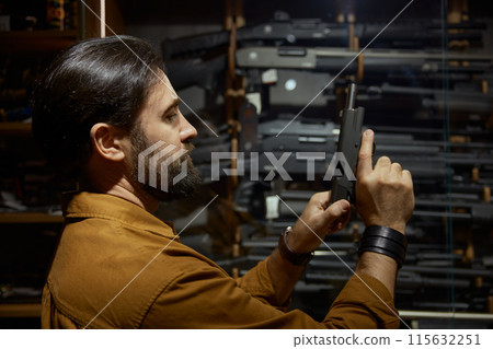 Male retailer or client checking handgun portrait with selective focus Male retailer or client checking handgun portrait with selective focus 115632251