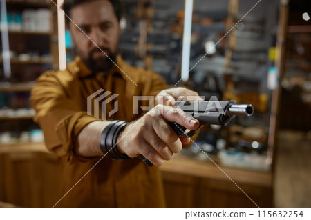 Male retailer or client checking handgun portrait with selective focus Male retailer or client checking handgun portrait with selective focus 115632254