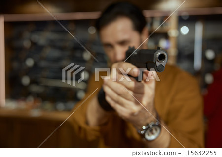 Male client choosing handgun in weapon shop, closeup view on gunpoint 115632255