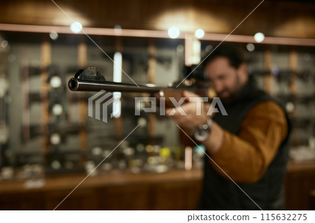 Man entrepreneur checking gun aiming telescopic sight at weapon store 115632275