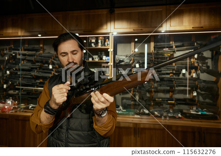 Man entrepreneur checking gun aiming telescopic sight at weapon store 115632276