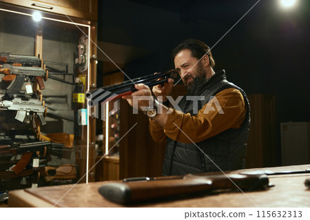 Weapon shop owner cleaning gun with brush preparing goods for sale 115632313