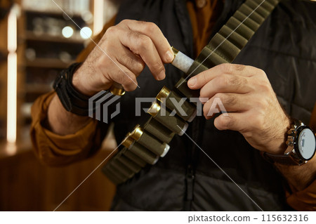 Hunter hands placing bullets into the ammo belt closeup 115632316