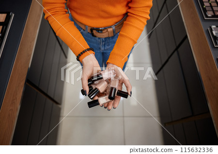 Woman holding nail polish in cosmetics store 115632336
