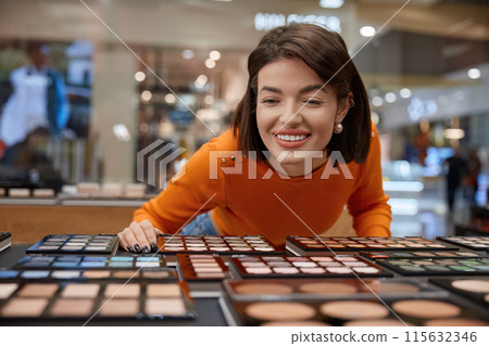 Smiling woman leaned to stand with eye shadow palettes different shades Smiling woman leaned to stand with eye shadow palettes different shades 115632346