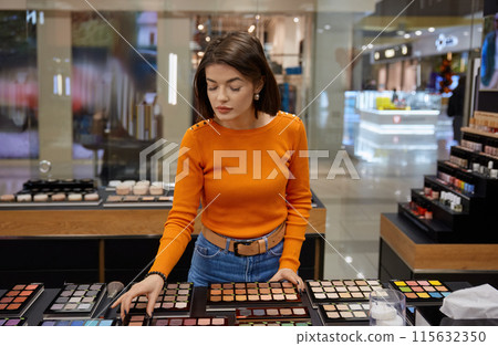 Beautiful lady looking for eye shadow palette in cosmetics shop Beautiful lady looking for eye shadow palette in cosmetics shop 115632350