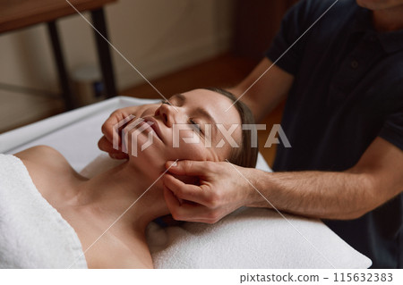 Woman getting face massage beauty procedure in luxury spa salon Woman getting face massage beauty procedure in luxury spa salon 115632383