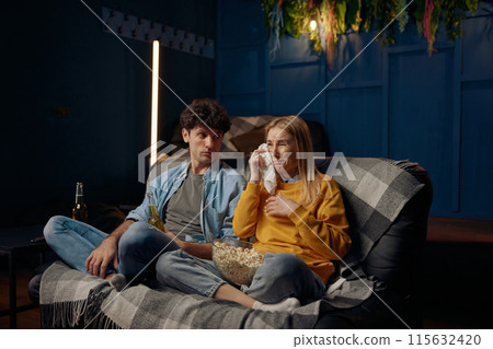 Man and crying woman watching emotional film with popcorn together 115632420