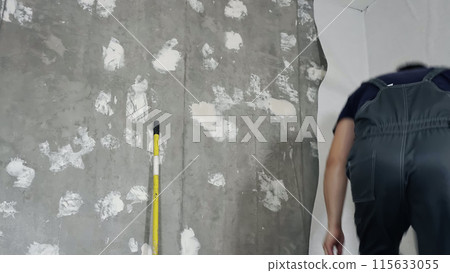 A man glues wallpaper on the floor in a room, Time lapse 115633055