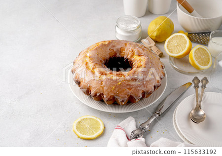 Lemon bundt cake drizzled with powdered sugar glaze on a light table with copy space for recipe 115633192
