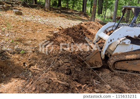 Tractor leveling ground at an earthmoving site in preparation for construction work is backyard Tractor leveling ground at an earthmoving site in preparation for construction work is backyard 115633231