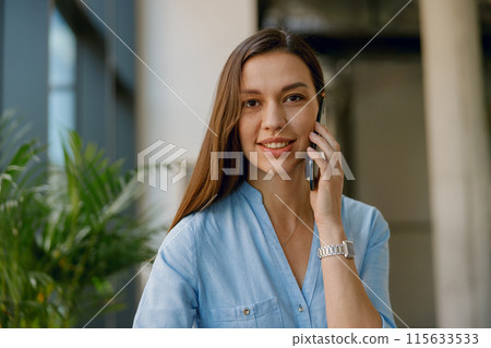Professional businesswoman talking on the phone in her office, engaged in business communication 115633533