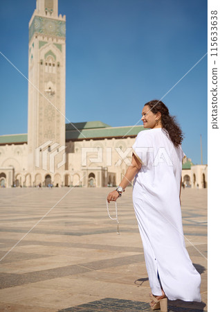 Woman in traditional attire with prayer beads standing in front of a mosque on a sunny day Woman in traditional attire with prayer beads standing in front of a mosque on a sunny day 115633638