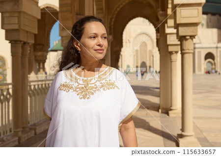 Smiling woman in traditional clothing standing in a historic architectural setting 115633657
