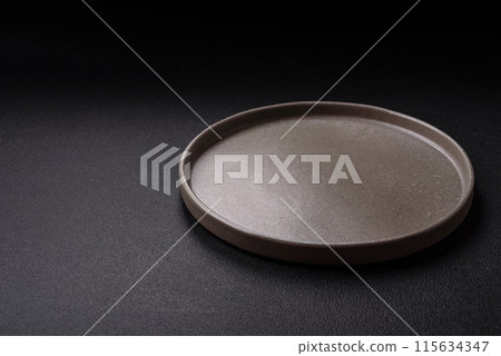 Empty ceramic round plate on dark textured concrete background 115634347