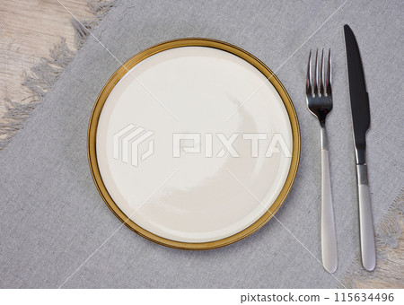 Round empty white ceramic plate, knife and fork on the table, top view Round empty white ceramic plate, knife and fork on the table, top view 115634496