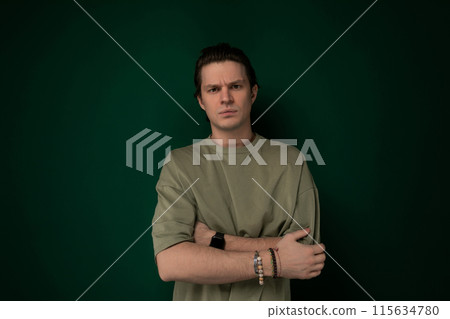 Man Crossing Arms in Front of Green Wall 115634780