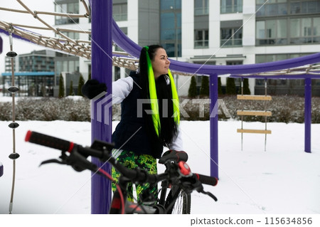 Woman Standing Next to Bike in Snow 115634856