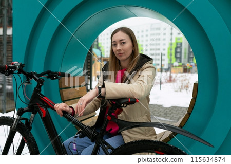 Woman Sitting on Bench Next to Bike 115634874