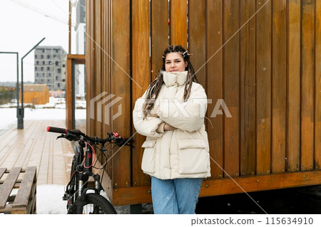 Woman Standing Next to Bike in Front of Building Woman Standing Next to Bike in Front of Building 115634910