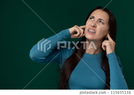 Woman in Blue Shirt Holding Hand to Ear Woman in Blue Shirt Holding Hand to Ear 115635138
