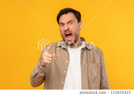 A man with angry expression on his face, eyebrows raised and mouth slightly open in shock. His eyes are wide and focus intently on something off-camera, conveying astonishment and disbelief. 115635423