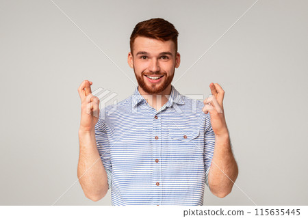 Positive millennial guy crossing fingers and making wish on beige background, panorama Positive millennial guy crossing fingers and making wish on beige background, panorama 115635445