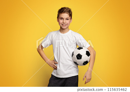 Kid in white t-shirt holding soccer ball on orange panorama background with empty space 115635462