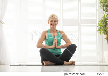 Portrait Of Beautiful Senior Woman Practicing Yoga In Lotus Position At Home, Happy Sporty Mature Female In Activewear Meditating On Fitness Mat In Light Room, Smiling At Camera, Copy Space Portrait Of Beautiful Senior Woman Practicing Yoga In Lotus Position At Home, Happy Sporty Mature Female In Activewear Meditating On Fitness Mat In Light Room, Smiling At Camera, Copy Space 115635593