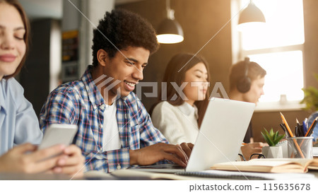 Intelligent afro guy studying with laptop and books at library, preparing for final exams Intelligent afro guy studying with laptop and books at library, preparing for final exams 115635678