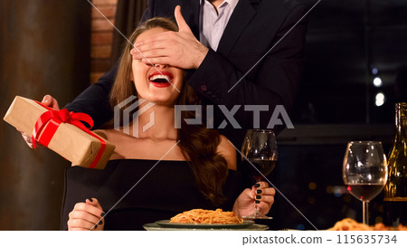 Happy man giving a surprise Valentine's day present to his girlfriend. Surprise on Valentine day concept, copy space 115635734