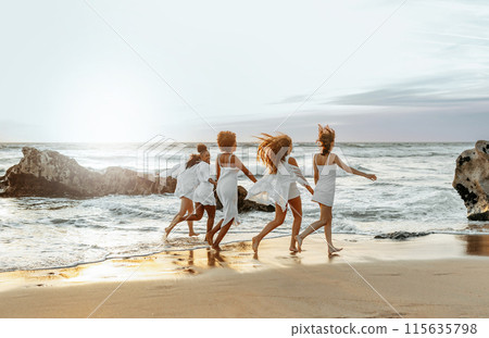 Happy young female friends having fun and celebrating hen party while running on the beach at the sunset, enjoying evening at coastline, free space Happy young female friends having fun and celebrating hen party while running on the beach at the sunset, enjoying evening at coastline, free space 115635798