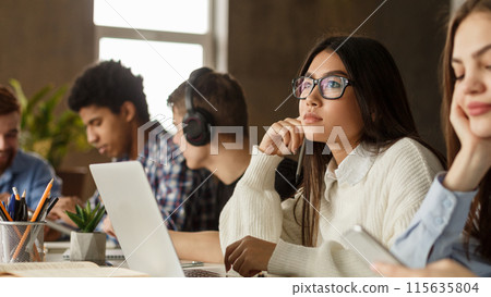 Studying in college library. Thoughtful girl using laptop, preparing for final exam 115635804