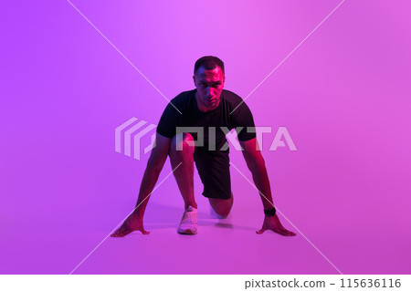 Front View Of Motivated African American Runner Guy Doing Crouch Start And Looking At Camera, Sportsman Posing Ready For Race On Purple Neon Background. Fit Man Preparing For Running Workout 115636116