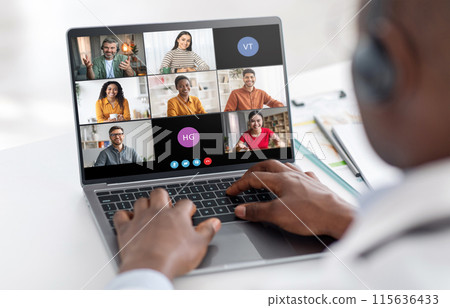 A man sits at a desk, his hands typing on a laptop keyboard, while participating in a video conference. The screen shows six participants in individual video frames. 115636433