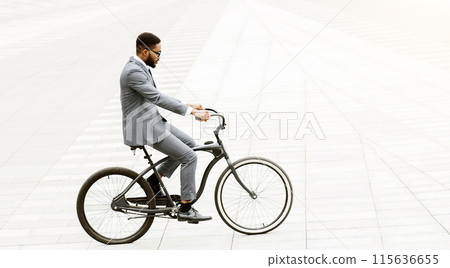 An African American professional is cycling through the city. The setting is urban and busy, highlighting the blend of business efficiency and active commuting. 115636655