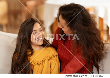Mom And Daughter Bond. Portrait Of Happy Arabic Preteen Girl Smiling And Talking To Mommy, Enjoying Time Together On Living Room Sofa At Home. Family, Good Relationship With Mother. Selective Focus 115636700