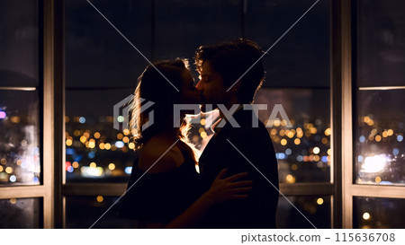 Couple in love kissing on panoramic window background overlooking night city. Love, relationships, affection concept Couple in love kissing on panoramic window background overlooking night city. Love, relationships, affection concept 115636708