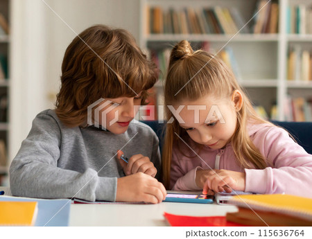 School kids friends using smartphone and playing games online, sitting in classroom interior, having fun with mobile phone app at school School kids friends using smartphone and playing games online, sitting in classroom interior, having fun with mobile phone app at school 115636764