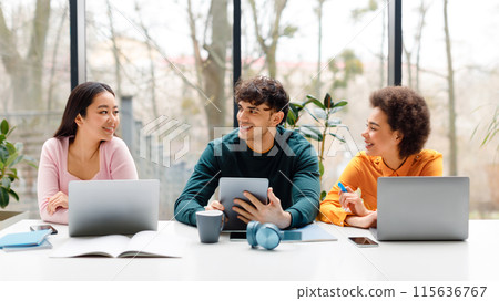 Happy diverse three students using various gadgets and chatting, sitting in university audience, learning for exams, guy and ladies making online research, panorama Happy diverse three students using various gadgets and chatting, sitting in university audience, learning for exams, guy and ladies making online research, panorama 115636767
