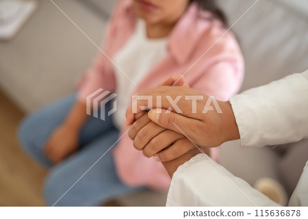 A close up shot showing the hands of a therapist and a patient holding each other. The patients hand is visible in the foreground and is being held by the therapists hand. A close up shot showing the hands of a therapist and a patient holding each other. The patients hand is visible in the foreground and is being held by the therapists hand. 115636878