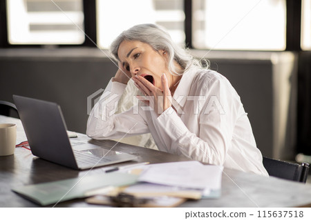 Fatigue Issue. Bored Middle Aged Businesswoman Yawning Looking At Laptop Computer, Tired Of Office Work Routine Sitting At Workplace Indoor. Manager Lady Strugging With Boring Business Tasks 115637518