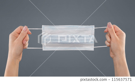 Female hands holding medical protective mask on grey background, panorama 115637571