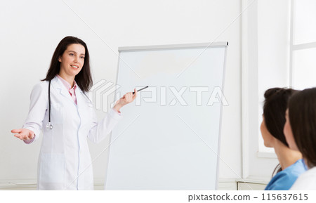 Medical Lecture. Woman Telling Theory To Interns Using Whiteboard And Pictures Medical Lecture. Woman Telling Theory To Interns Using Whiteboard And Pictures 115637615