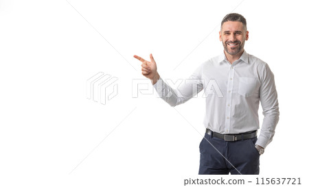 A smiling man dressed in business attire points confidently with his index finger against a clean, white background. The man exudes a professional yet approachable demeanor, copy space 115637721