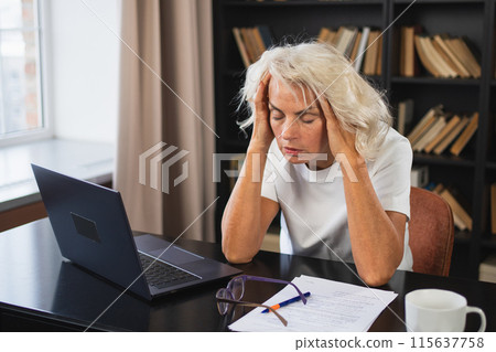 Headache pain. Middle aged woman touching temples experiencing stress. Mature old lady tired of work feeling headache sick rubbing temples forehead. Long laptop usage computer vision office syndrome Headache pain. Middle aged woman touching temples experiencing stress. Mature old lady tired of work feeling headache sick rubbing temples forehead. Long laptop usage computer vision office syndrome 115637758